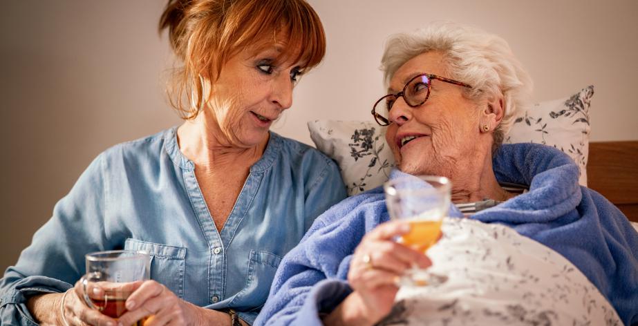 Mantelzorger en senior drinken samen thee